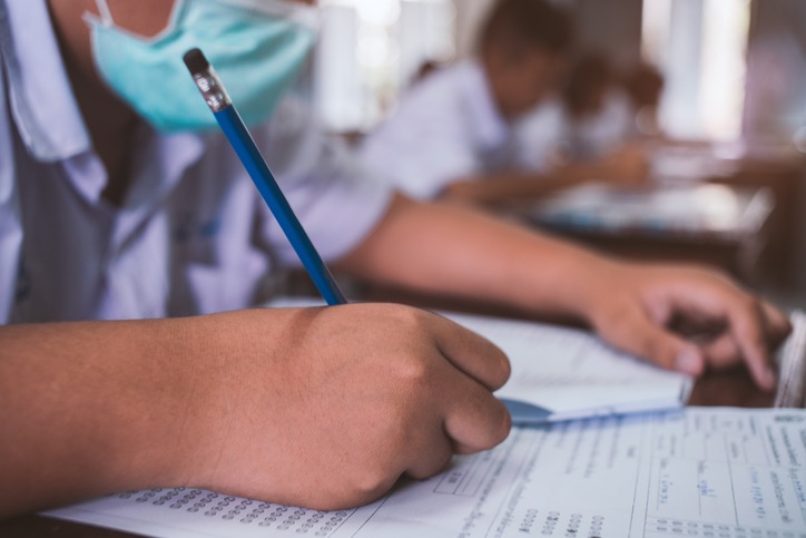 Students wearing mask for protect corona virus or covid-19 and doing exam in classroom with stress.