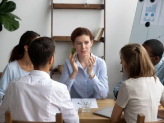Five businesspeople brainstorming during briefing in boardroom