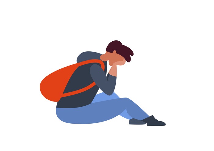 Sad guy with a backpack sitting on the floor. Depression, negative emotions, loneliness in adolescence, at school
