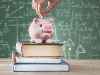 Person putting money into piggy bank with school background
