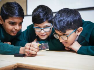 Three primary school kids look at micro:bit