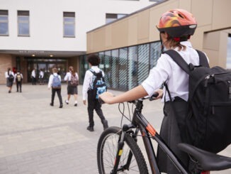 Kid walking to school entrance with bike