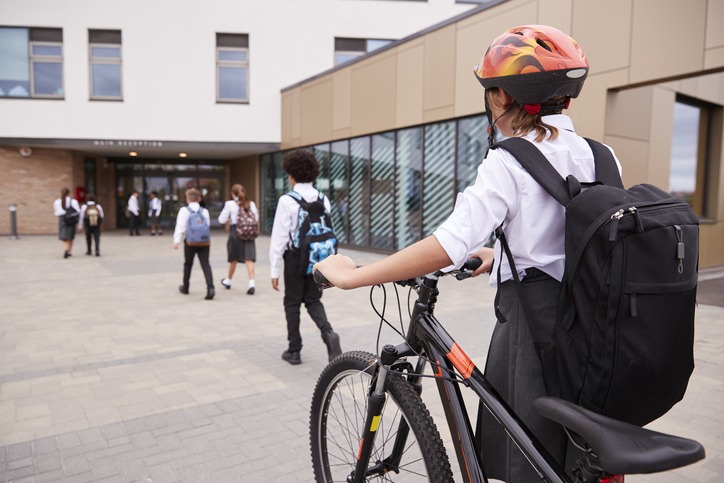 Kid walking to school entrance with bike
