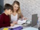 Boy doing homework while homeschooling mom teaches