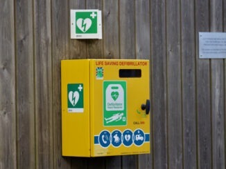 Defibrillator attached to the wooden wall in a park.
