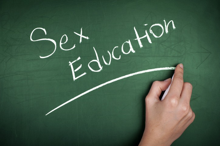 Woman hand writing 'Sex Education' on green blackboard