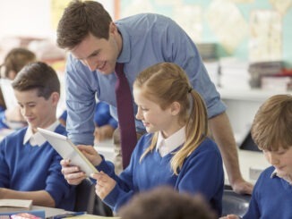 Teacher with his pupils in classroom using tablet pc