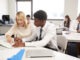 High School Tutor Giving Uniformed Male Student One To One Tuition At Desk In Classroom