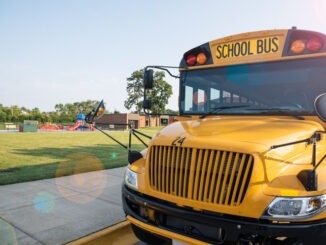 Yellow school bus parked next to playground