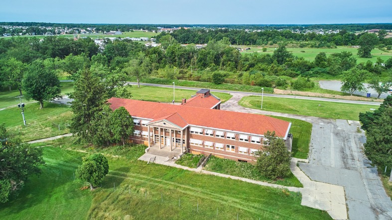 Aerial of stunning abandoned brick building with stone pillar entrance.jpg