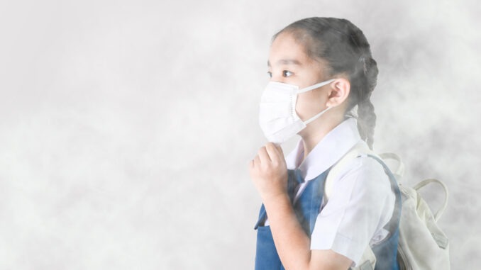Portrait Asian children girl wear  mask to protect PM 2.5 dust and air pollution. Portrait of Thai student wearing protection mask  bad weather, pm2.5 concept background