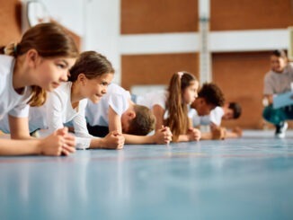 Group of elementary students having physical education class at school gym.