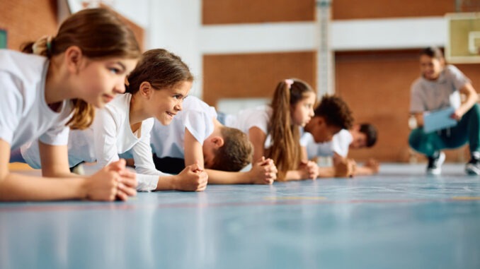 Group of elementary students having physical education class at school gym.
