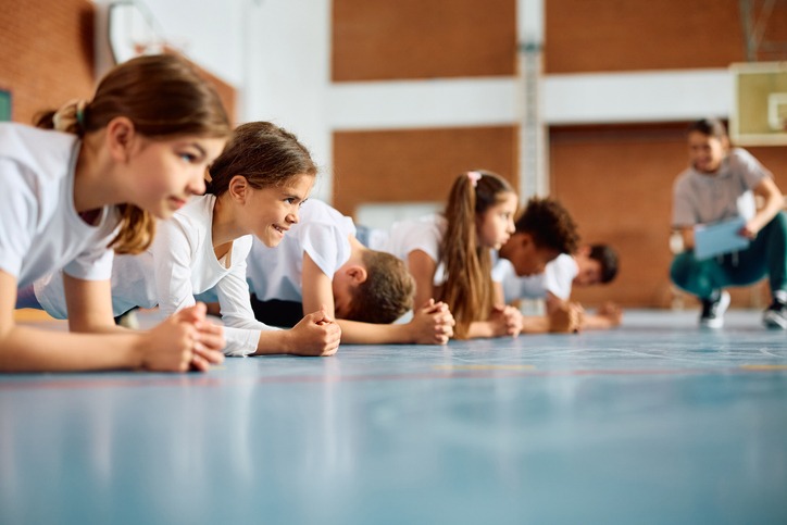 Group of elementary students having physical education class at school gym.