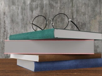Spectacles on a stack of hardcover books of different colors on a wooden table. Illustration of the concept of learning, studying and education