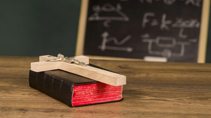 A crucifix on a book against the background of a chalkboard