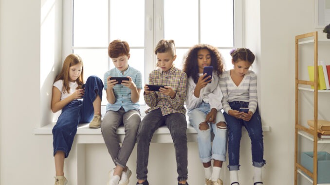 Des enfants de différentes nationalités jouent à des jeux en ligne ou lisent les réseaux sociaux sur leurs téléphones portables.