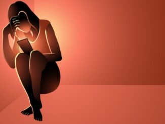 Depressed woman sitting in a corner holding a smart phone