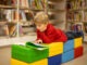 Adorable little boy, sitting in library, reading book and choosing what to lend, kid in book store