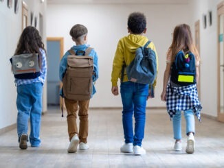 Back view of group of school kids walking in corridor.