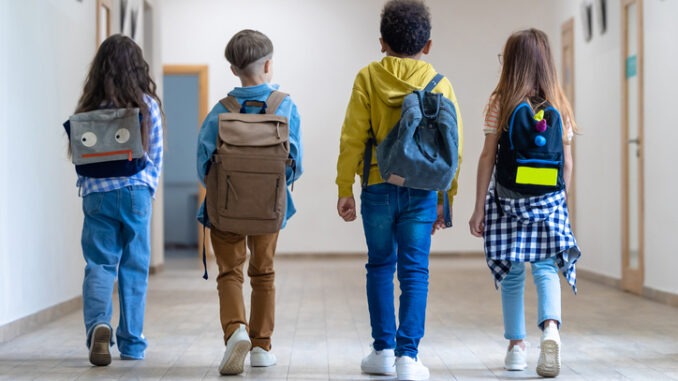 Back view of group of school kids walking in corridor.