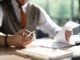 Businessman hands holding pen for working with stack of paper files, searching information, business report