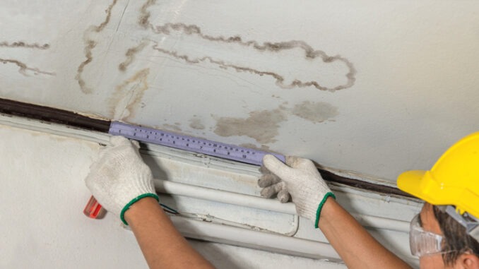 Worker fix leaking pipe in ceiling ,close-up of a stain on the ceiling.