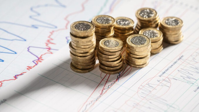 Stack of pound coins on financial graphs and figures 