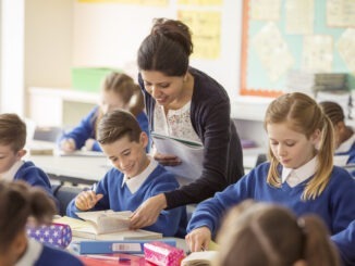 Female teaching assistant with her pupils in classroom