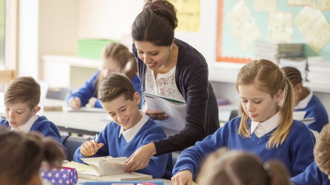 Female teaching assistant with her pupils in classroom