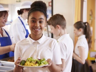 Schoolgirl holds a plate of food in a school cafeteria