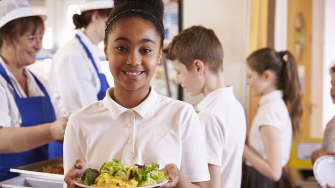 Schoolgirl holds a plate of food in a school cafeteria