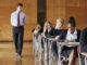 Teenage Students Sitting Examination With Teacher Invigilating