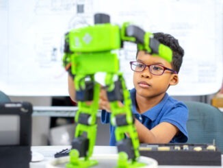 An african american boy use screwdriver setting robot kit.