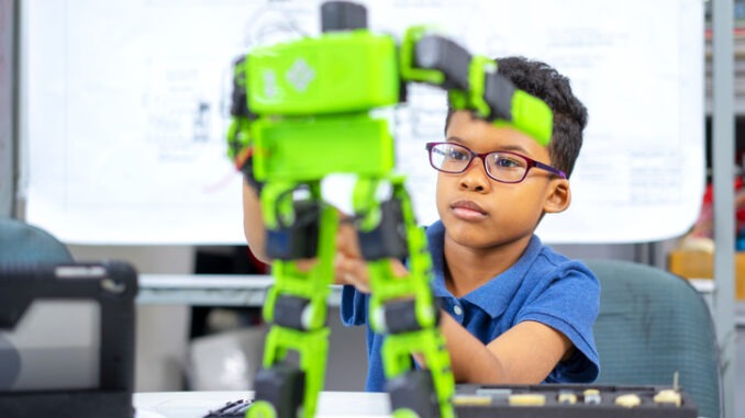 An african american boy use screwdriver setting robot kit.