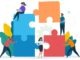People working together with giant puzzle elements. Symbol of partnership and collaboration.