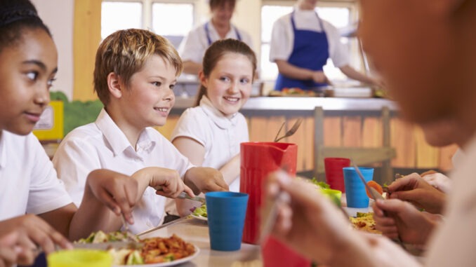 Primary school kids at a table in school cafeteria,