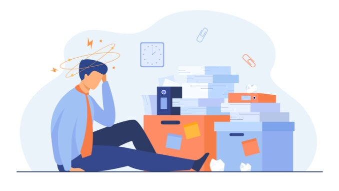 Tired man sitting on floor with paper document piles