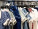 Various colors school uniform dresses for girls on hangers on the rack at the shop.