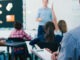 Male Trainee Teacher Being Observed Teaching In Classroom By Supervisor