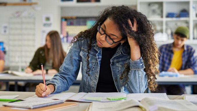 Troubled and stressed girl doing exam that doesn't know the answers.