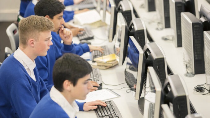 Teenage students using computers in computer room