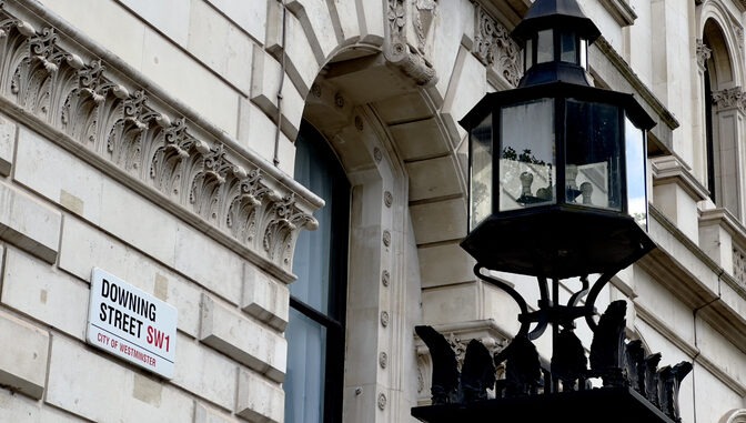 Downing Street sign on the wall of a government building in Westminster, London, UK.