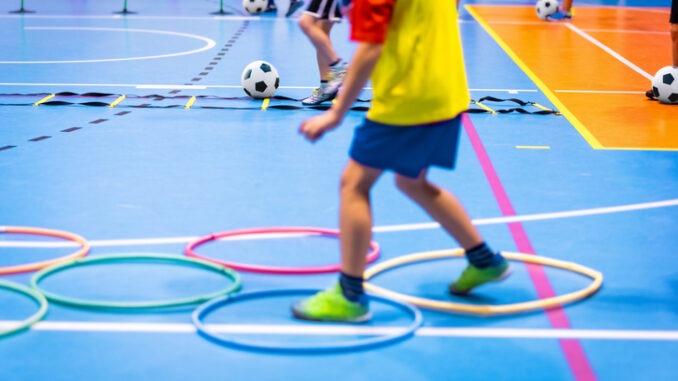 Indoor Soccer Class for Kids at School Sports Hall. Children Kicking Soccer Balls on Wooden Futsal Floor. Sport Football Practice For Preschool Boys