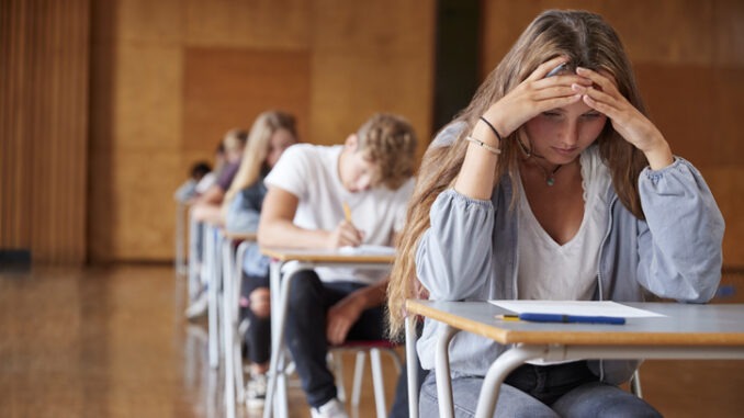 Anxious Teenage Student Sitting Examination In School Hall
