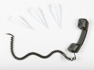 Call center concept, public relations, gossip, rumors. Telephone receiver with wire on a white background and paper airplanes.