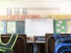 School classroom concept. New canvas school bag hanging classroom student chair in large modern classroom with blackboard back to school concept