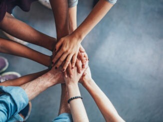 Close up top view of young people putting their hands together. Friends with stack of hands showing unity.