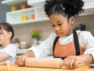 Happy children girls with bread and cookies playing with flour and laugh in kitchen, Little girls making bread in the kitchen, Children standing at cooking counter preparing ingredient for dinner meal