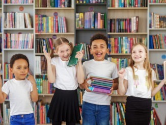Four children holding stack of books in library. Multiethnic classmates having fun. World Book Day. Benefits of everyday reading.